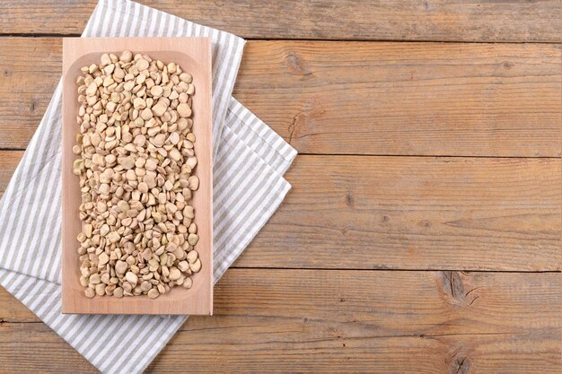 Cicerchia or indian pea on a wooden plate with napkin on natural wooden background, food gluten free.