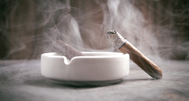 Cigar and ashtray on table. Smoking