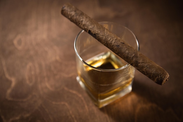 Cigar lies on a glass with whiskey