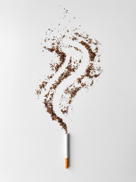 Photo cigarette with tobacco spilling out in smoke trail shape on white background symbolizing smoking