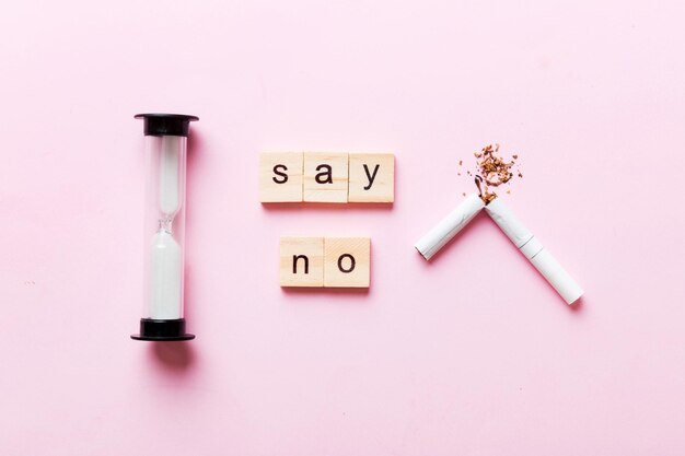 Cigarette And Wooden Blocks Broken cigarette on table background with hourglass No Tobacco Day with hourglass clock health concept time to quit smoking