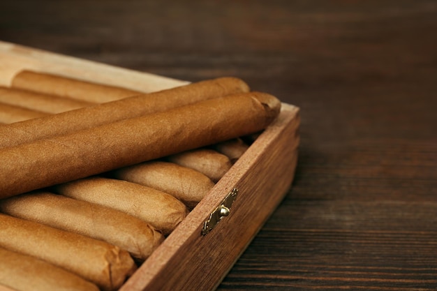 Cigars in humidor on wooden table closeup