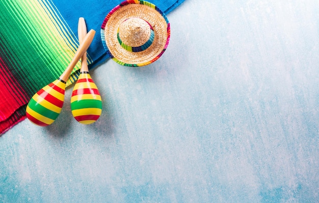 Cinco de Mayo holiday background made from maracas mexican blanket stripes or poncho serape and hat on blue background