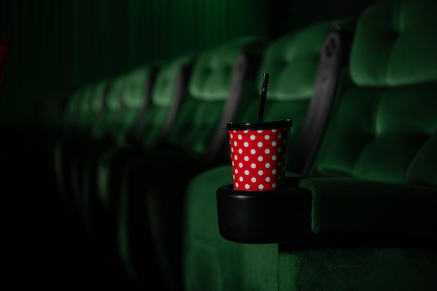 Photo cinema auditorium with green seats and a red cup of drink