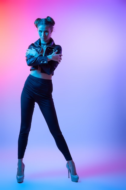 Cinematic night portrait of woman in  neon. High Fashion model girl in colorful bright neon lights posing in studio, portrait of beautiful woman in   coat and trousers.