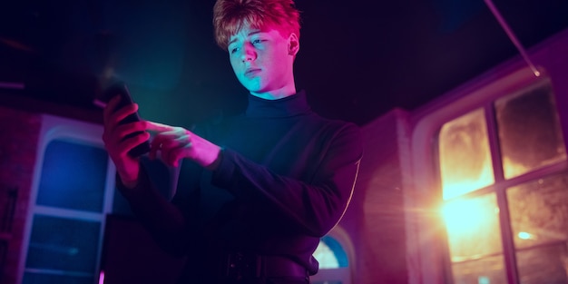 Cinematic portrait of handsome young man in neon lighted interior