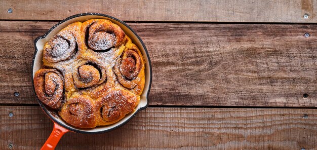 Cinnabon cinnamon rolls buns with pumpkin nut caramel and sugar cream iced on rustic wooden background table Top view Sweet Homemade Pastry christmas baking Kanelbule swedish dessert