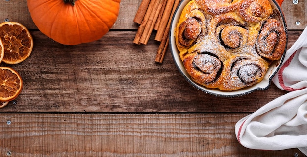 Cinnabon cinnamon rolls buns with pumpkin nut caramel and sugar cream iced on rustic wooden background table Top view Sweet Homemade Pastry christmas baking Kanelbule swedish dessert