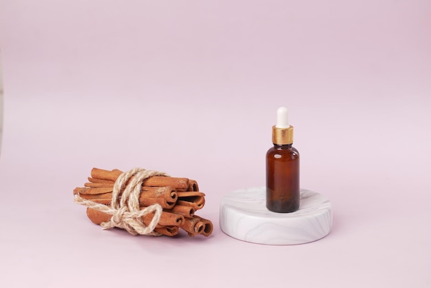 Cinnamon essential oil in a container on light purple background