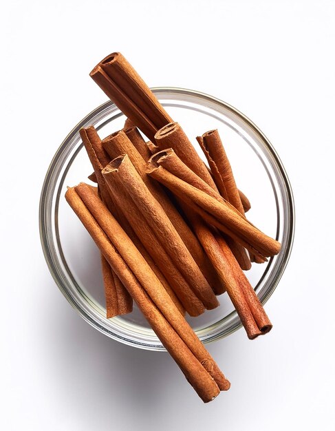 Photo cinnamon sticks in a transparent glass bowl isolated on white background