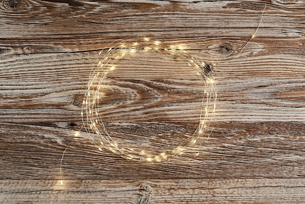 Circle frame made of lighting garland on wooden background