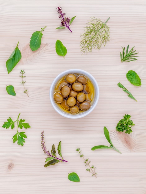 The circle of fresh herbs set up on white wooden background.