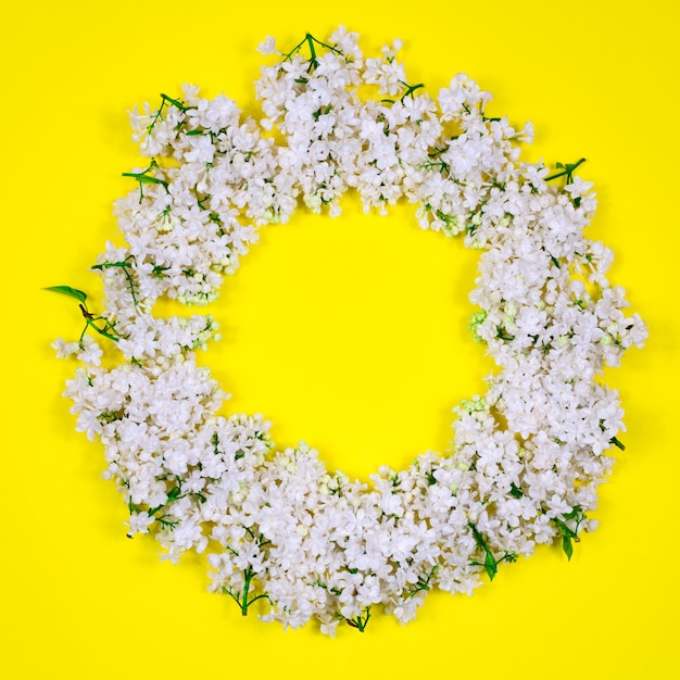 Circle of white lilac flowers on a yellow background Minimal floral concept Floral pattern as a layout for a greeting card copy space for your text Mothers Day Women's holiday