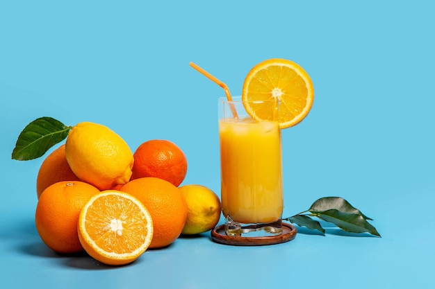 Citrus fruits and a glass of fresh juice on a blue background