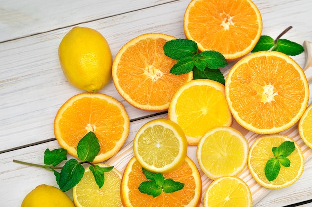 Citrus fruits. Oranges, lemons and mint. Cutted citrus fruits on a wooden background.