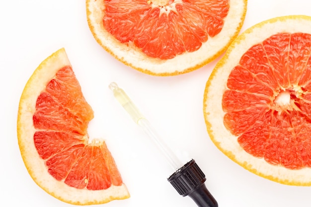 Citrus or grapefruit essential oil in glass bottle with fresh grapefruit on white background. Spa and skincare product