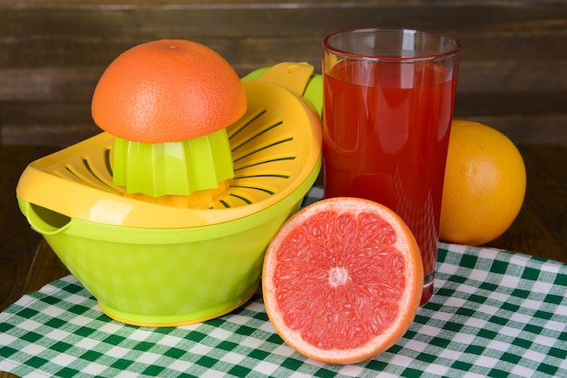 Citrus press and grapefruits on table on wooden background