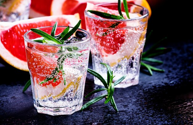 Citrus refreshing lemonade with rosemary and grapefruit black background selective focus