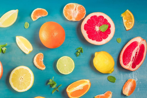 Citrus slices food pattern on blue background - assorted sliced citrus fruits with mint leaves, retro toned