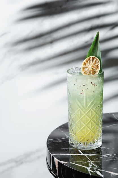 Citrus with kiwi cocktail or lemonade with sliced lemon near on marble table. concept of alcoholic or non-alcoholic drink hrad shadow on background