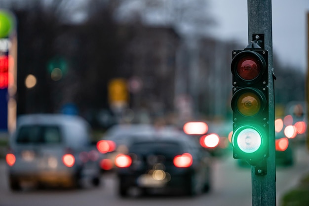 A city crossing with a semaphore on blurred background with cars in the evening streets green light