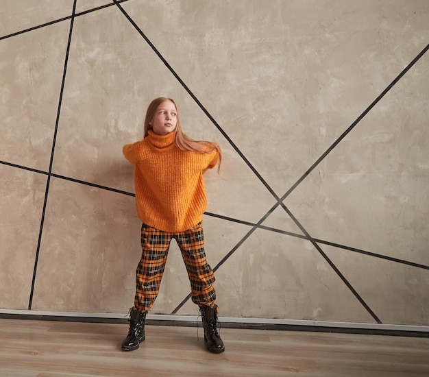 City girl in stylish clothes standing near the wall