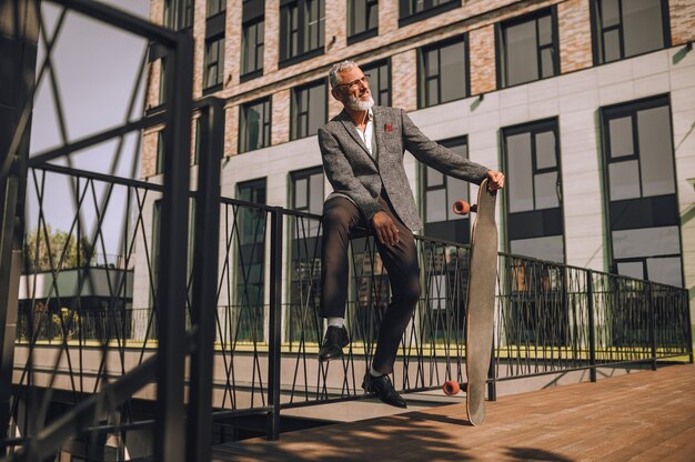 City life. A mature businessman with a skateboard in the office district