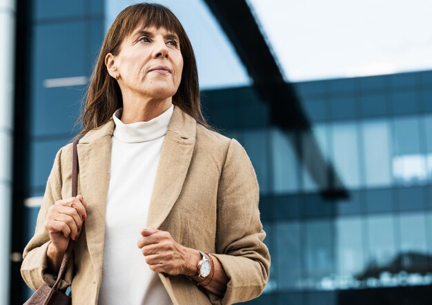 City office and senior business woman waiting for a lift taxi or cab outside the corporate building Serious professional and elderly manager standing alone outdoors in the street in a urban town