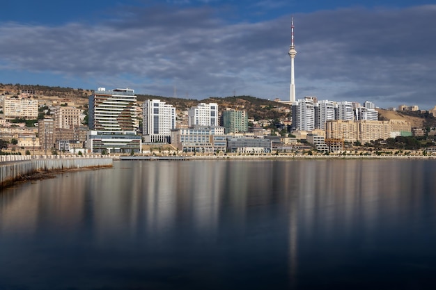 City skyline in sunlight with buildings on shore reflected in blurred sea water Baku Azerbaijan