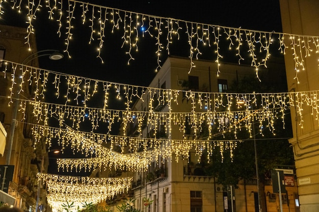 A city street with a large number of lights hanging from the buildings