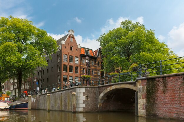 City view of Amsterdam canal, bridge and typical houses, boats and bicycles, Holland, Netherlands.