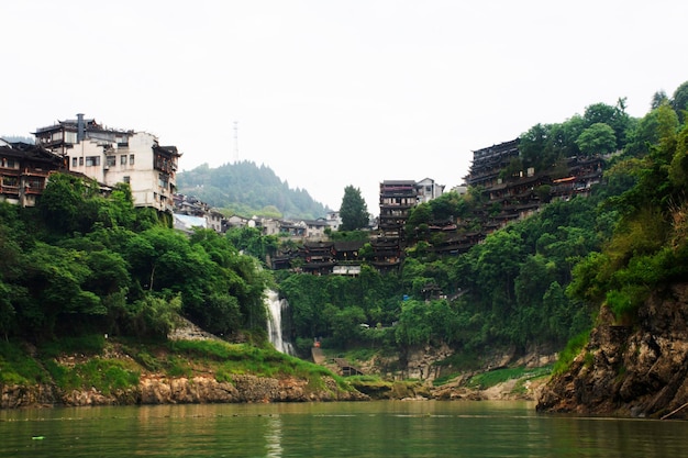 Photo cityscape historic buildings or heritage antique architectural of furong zhen tujia ancient town city and youshui river waterfalls for chinese travelers people travel visit at yongshun in hunan china