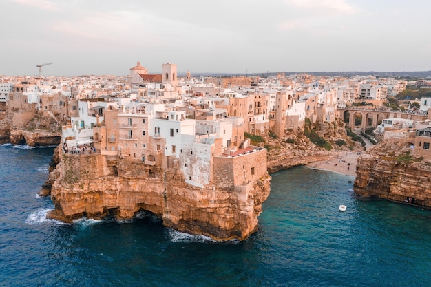 Cityscape of Polignano a Mare surrounded by the sea under a cloudy sky in Italy