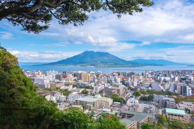 Cityscape with Sakurajima mountain, sea and blue sky background view 