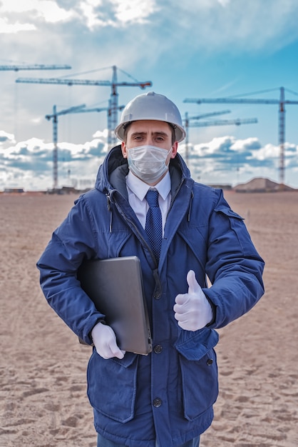 Civil engineer in a white helmet and blue jacket on the site