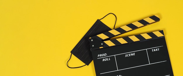 Clapper board or movie slate and black face mask on yellow blackground. Yellow and black color.