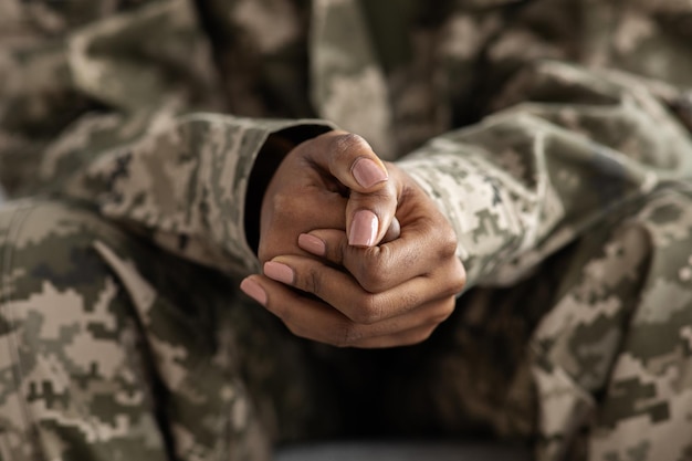 Clasped hands of black soldier woman in camouflage uniform closeup shot