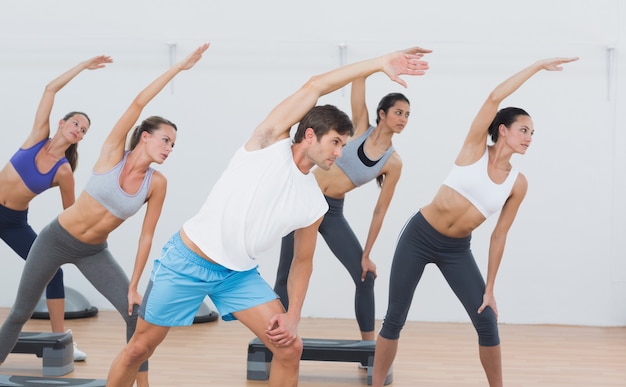 Class doing stretching exercise in fitness studio