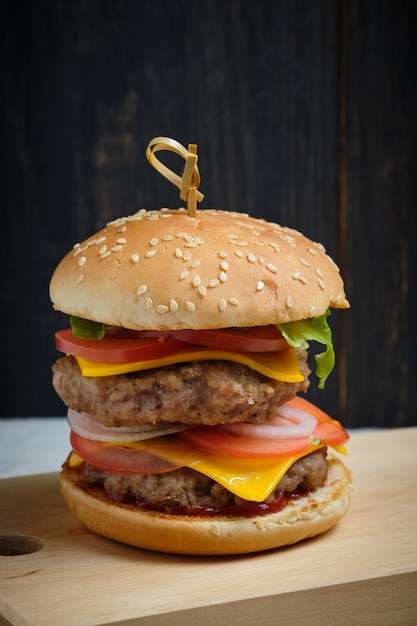 Classic American cheeseburger. One cheeseburger on a dark wooden background.