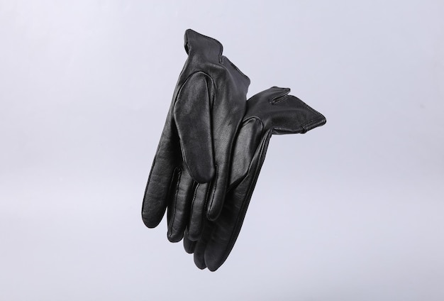 Classic black leather gloves levitating on gray background