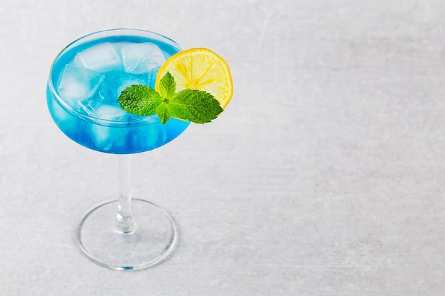 Classic  Blue Lagoon cocktail with lemon on modern on grey background