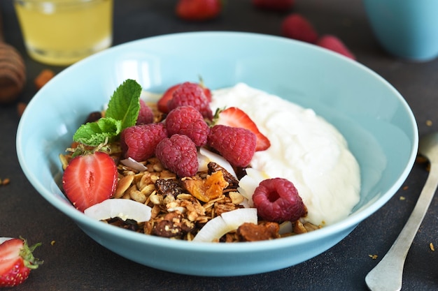 Classic breakfast granola with honey coconut yogurt and berries on a black background