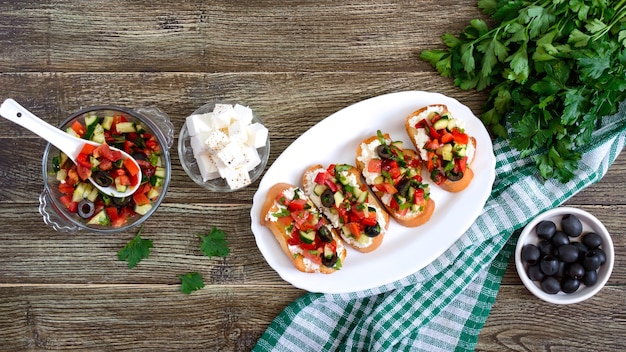 Classic bruschetta with tomatoes and feta on a white plate on a wooden table.