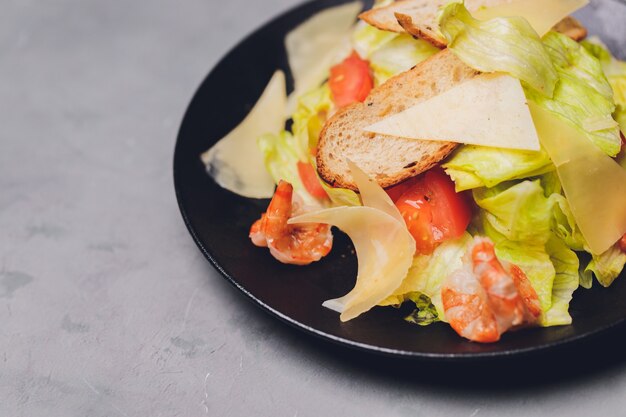 Classic Caesar salad with grilled chicken breast and half of egg in white ceramic plate. Served with ingredients above over old dark blue wooden background. Top view, space.