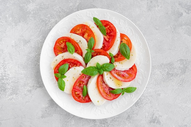 Classic caprese salad with mozzarella cheese tomatoes and basil on a white plate o