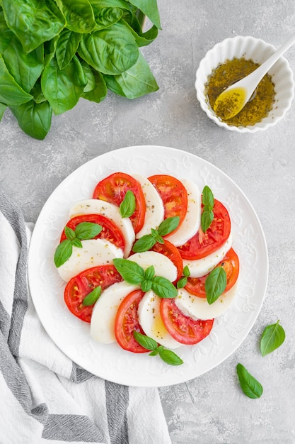 Classic caprese salad with mozzarella cheese, tomatoes and basil on a white plate