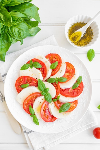 Classic caprese salad with mozzarella cheese tomatoes and basil on a white plate