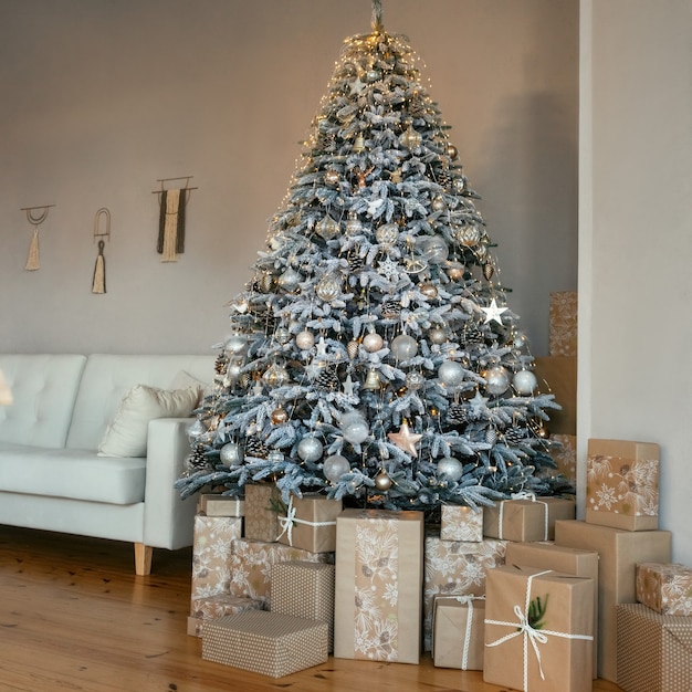 Classic christmas New Year decorated interior room. Christmas tree with gold and silver ornaments. A large beautifully decorated Christmas tree with gift boxes stands in room. Christmas eve at home.