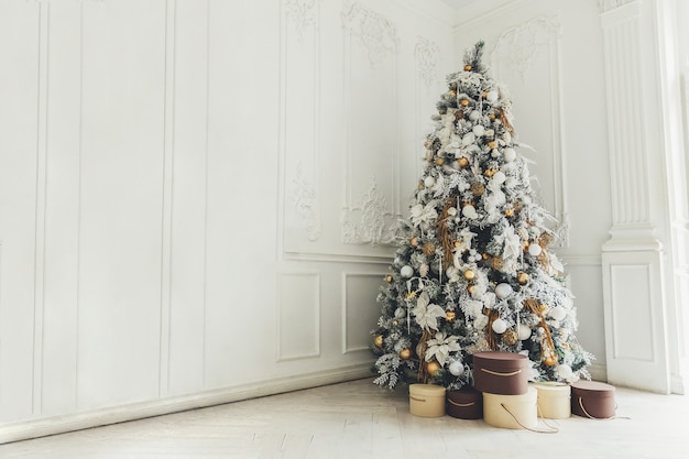 Classic christmas New Year decorated interior room New year tree. Christmas tree with gold decorations. Modern white classical style interior design apartment. Christmas eve at home.