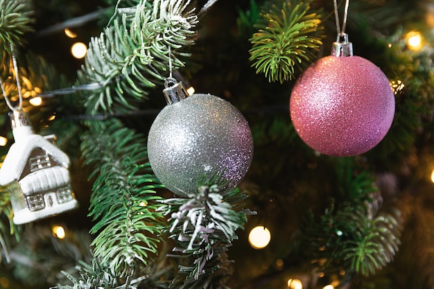 Classic Christmas New Year decorated New year tree with pink silver ornament decorations toy and ball and defocused garland lights Modern classical holiday design Christmas eve at home